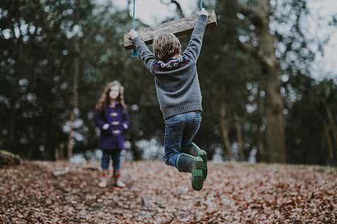 A boy holding on to a swing bench