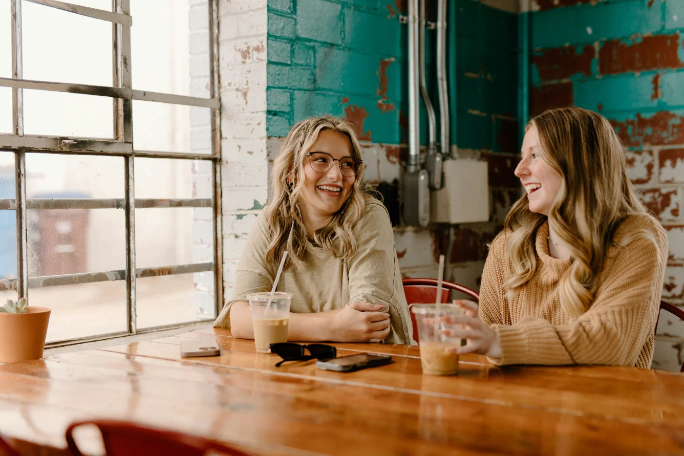 Two women laughing together at a wooden table