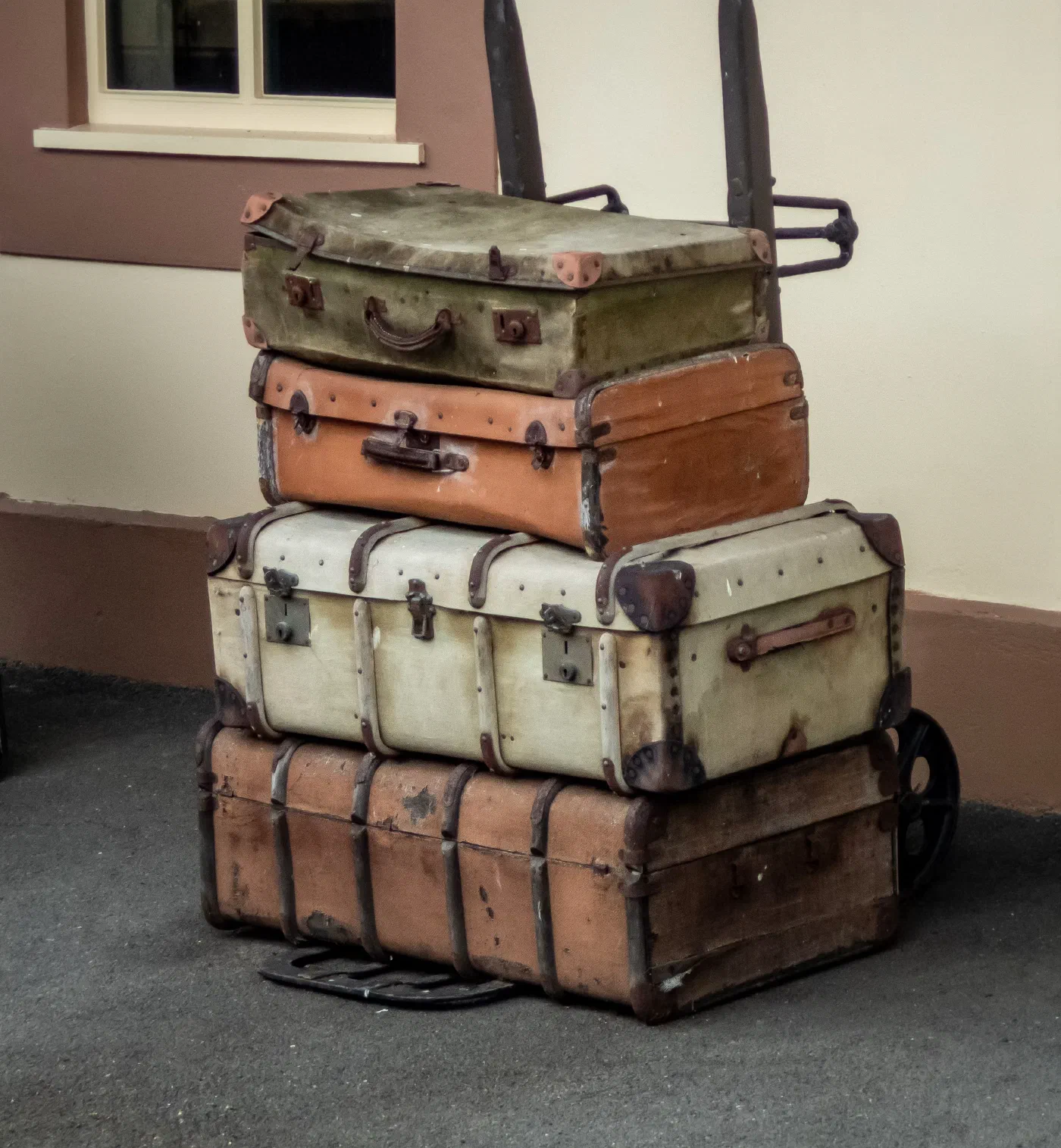 A stack of old suitcases in front of a building