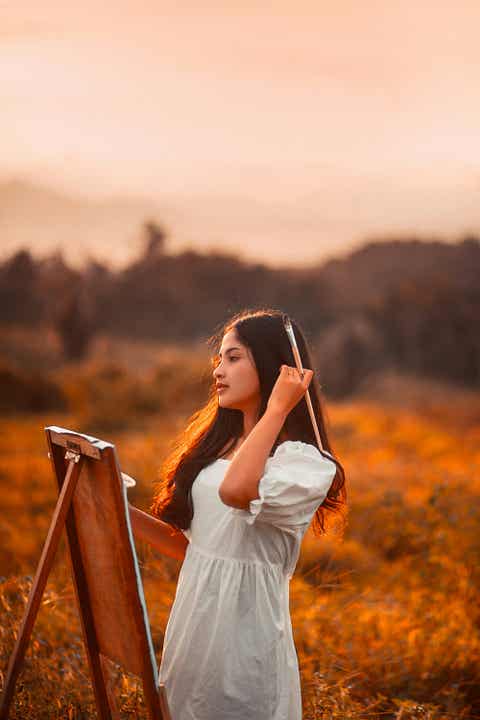 A woman in a white dress holding a paintbrush
